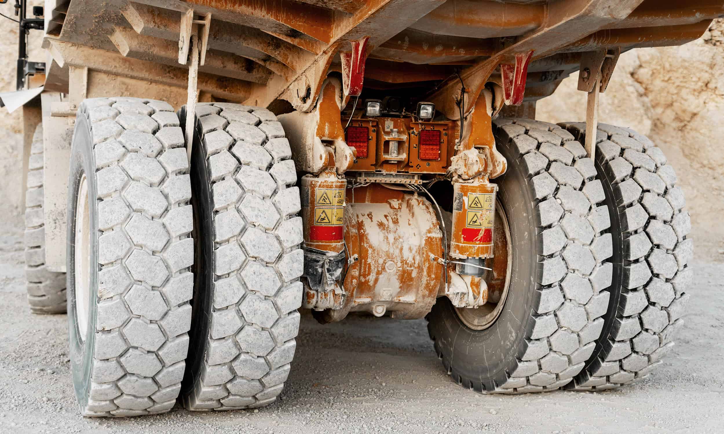 trailer axle repair service in the field. Two large tires on gravel.